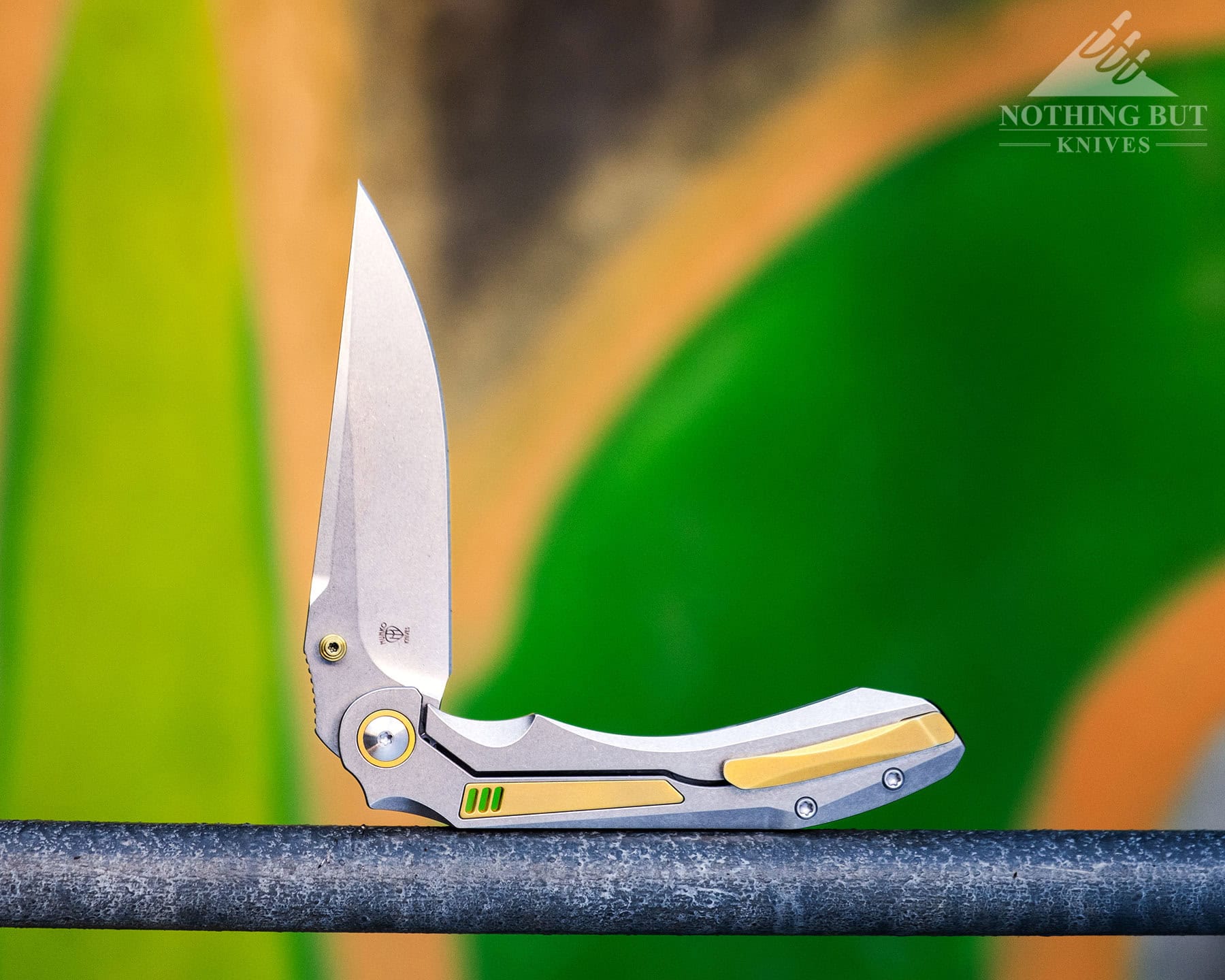 Orbital Fornax Review - Image 9 The Orbital Fornax folding knife shown here with the blade in the half open position in front of a graffiti covered cement wall.