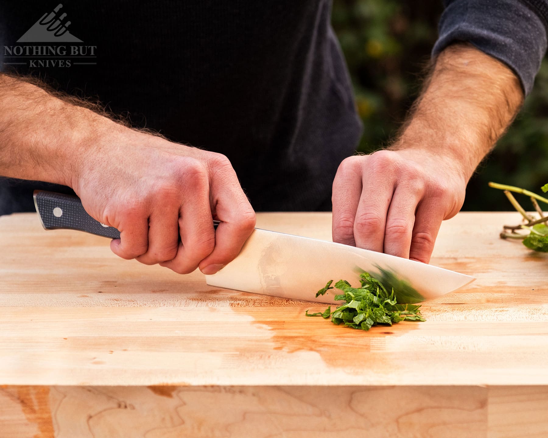 Zwilling Spectrum Chef'S Knife Review - Image 5 Zwilling 8 inch chef knife cutting herbs on a wooden cutting board.