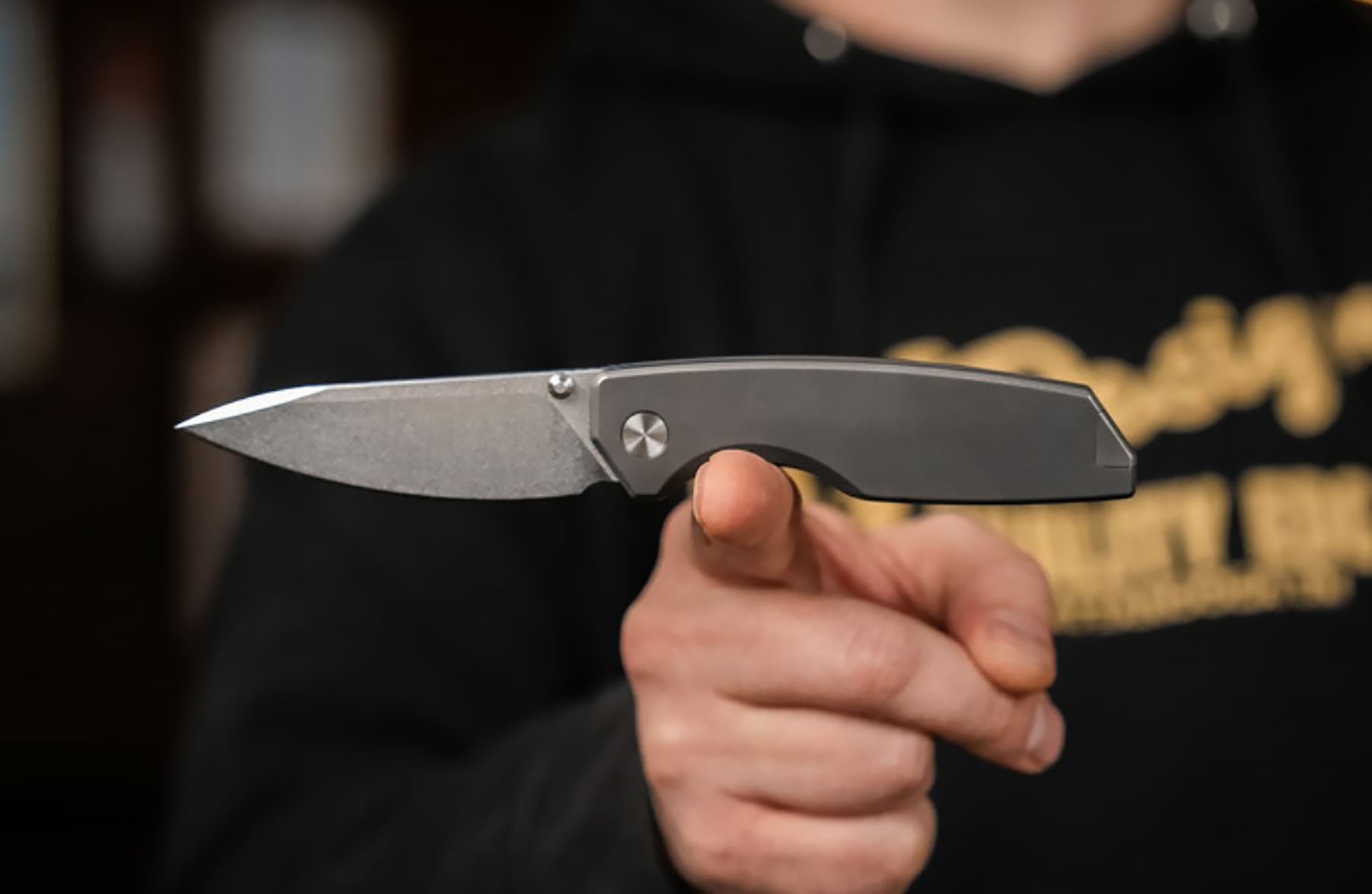 Big I Design Is Making A New Folder Designed By Ken Onion Jr. - Image 1 The Big i Design The Ti Manu pocket knife balanced on a person's index finger.
