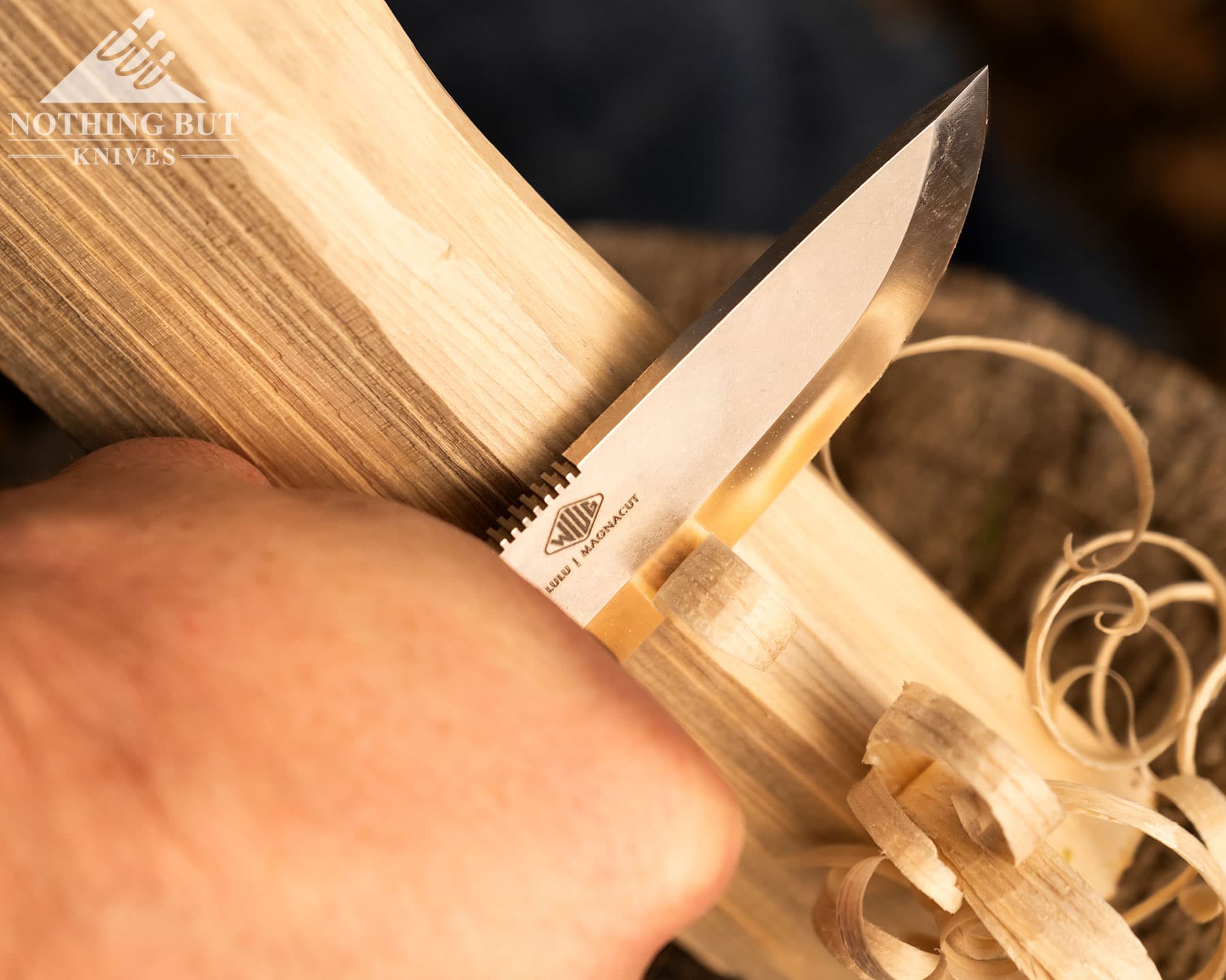 Knafs Lulu Review - Image 2 Knaf Bushcraft knife being held in the right hand carving wood on a wooden stump.