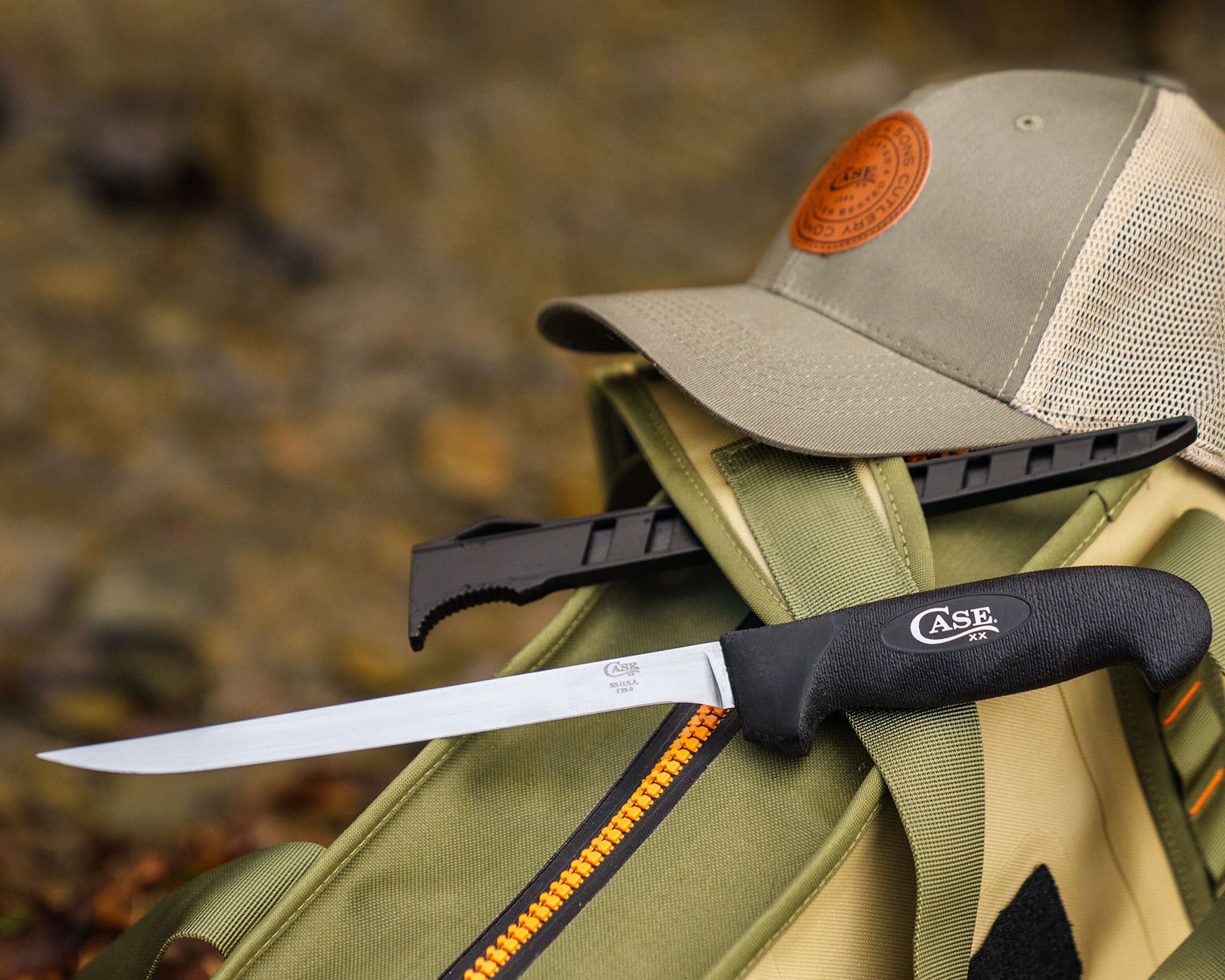 The Case 8-inch fillet knife with a black handle resting on a canvas backpack outdoors. 