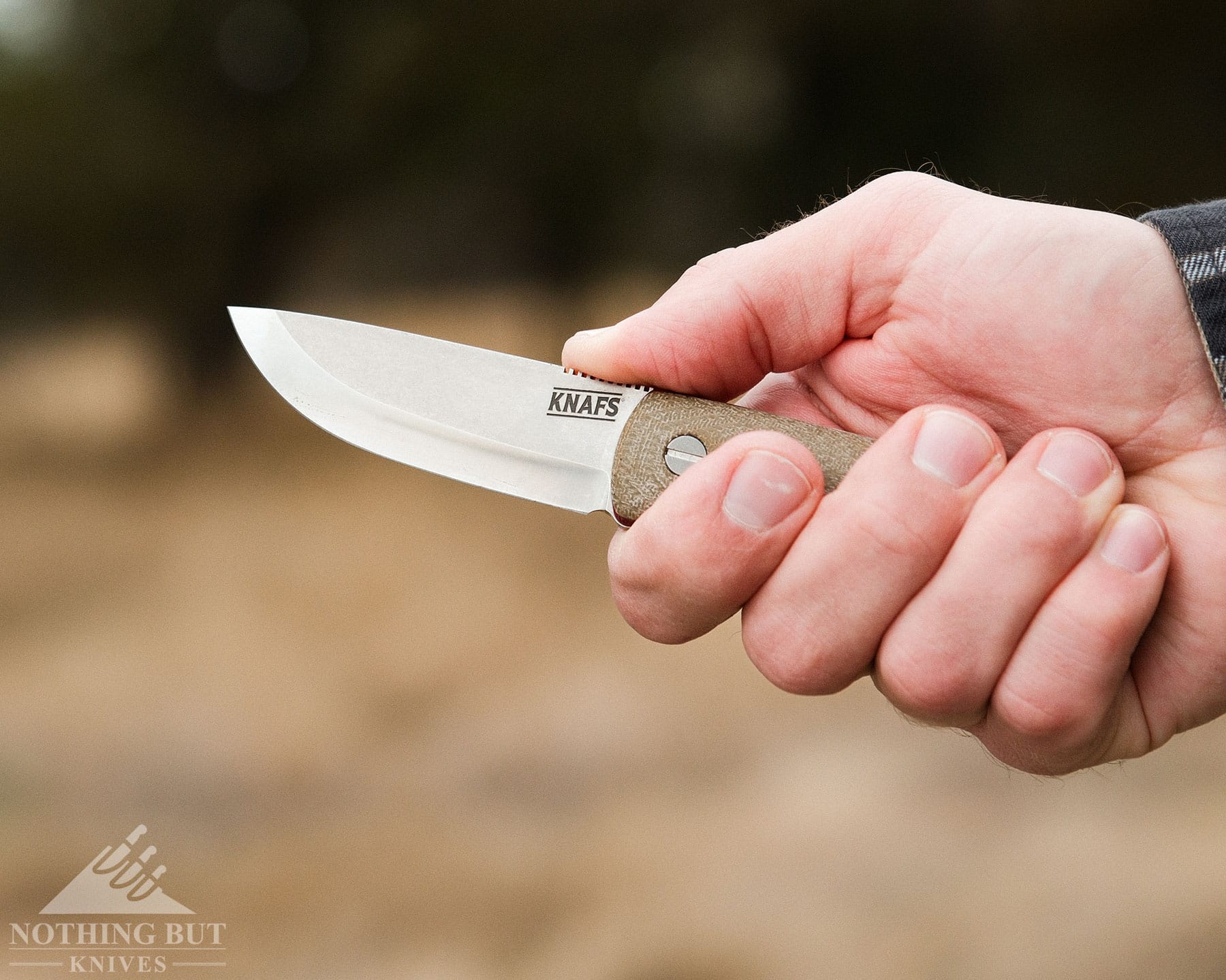 Knafs Lulu Review - Image 9 Knafs Lulu fixed blade held in the right hand of a man with a field in the background.