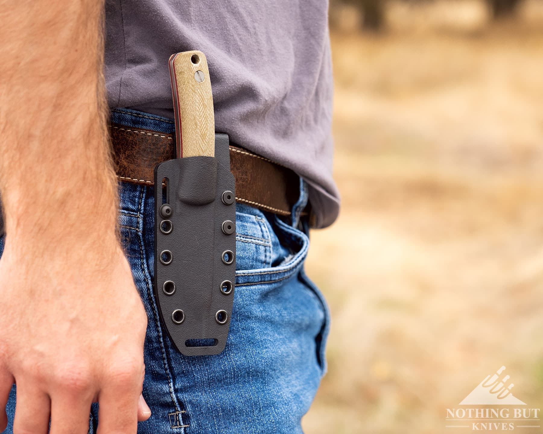 Knafs Lulu Review - Image 4 Knafs Lulu being carried vertically on a mans belt with a field in the background.