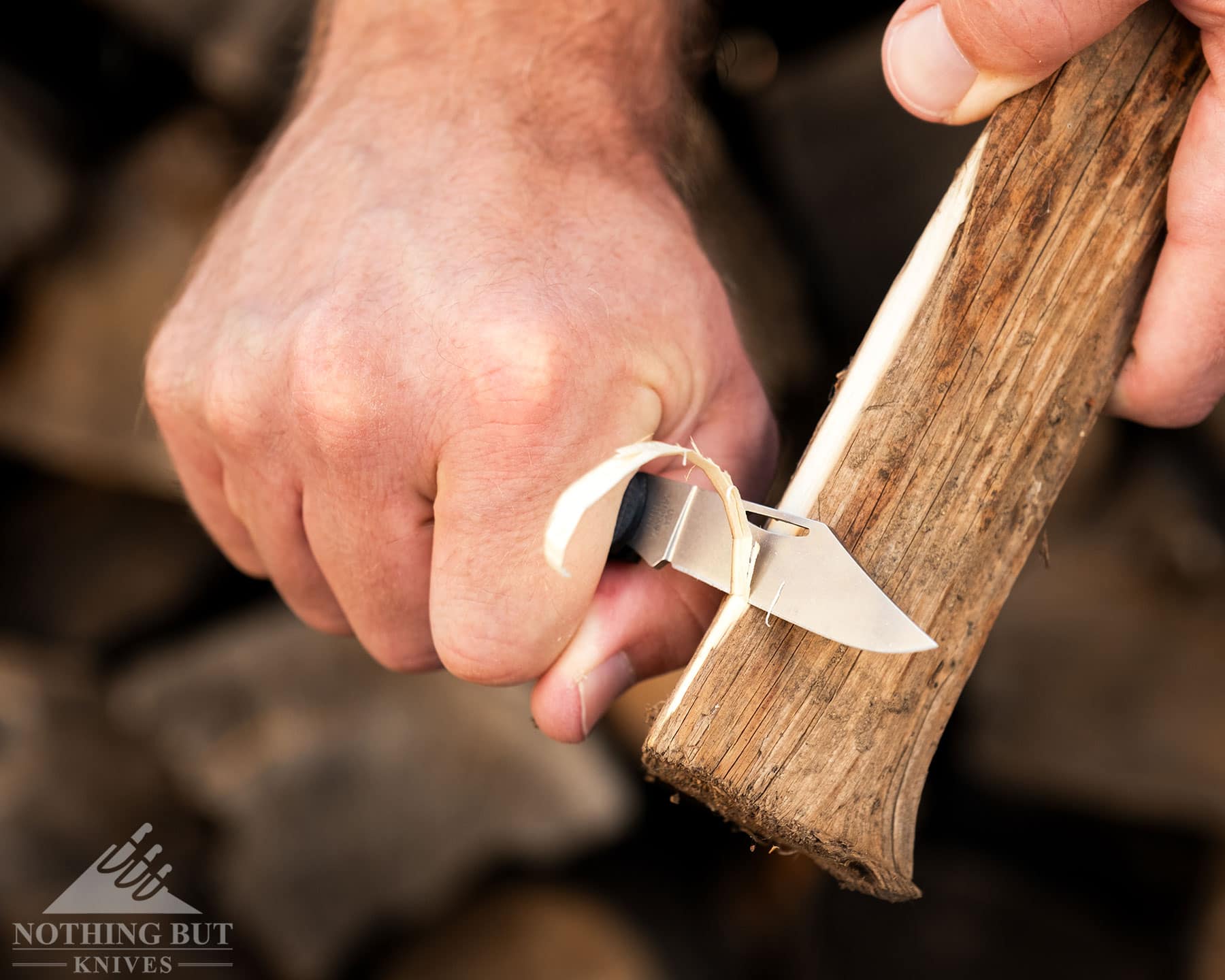 A close-up of the Case Crossroads Barlow being used to carve a piece of pine wood. 