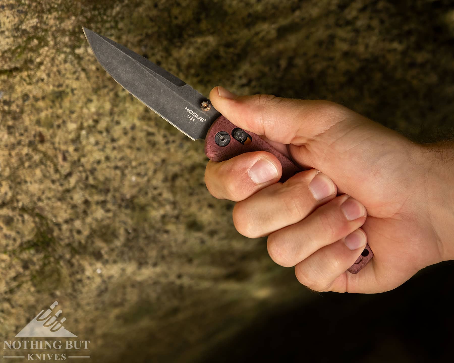 Hogue Mysto Review - Image 7 A close-up of the Hogue Mysto pocket knife being gripped in a person's right hand in front of a granite boulder.