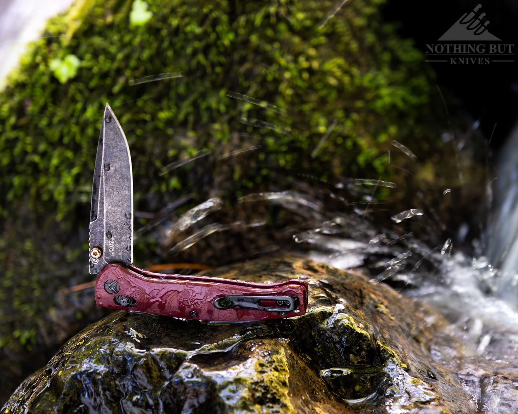 Hogue Mysto Review - Image 13 The Hogue Mysto knife with its blade in the half open position on a moss-covered rock in a mountain creek.