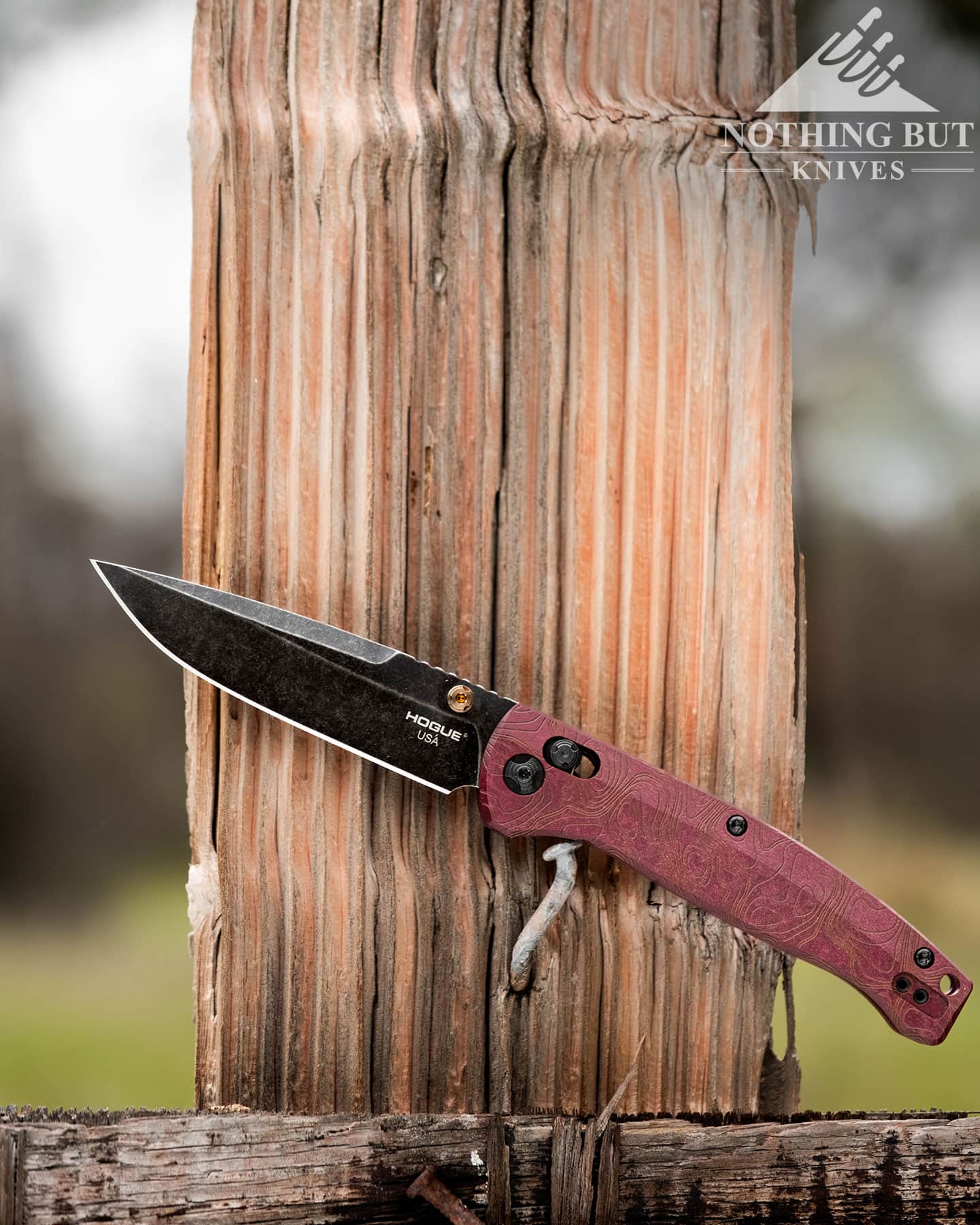 Hogue Mysto Review - Image 12 A Hogue folding knife shown here with its blade in the open position balanced on a rusty nail sticking out of a fence post.