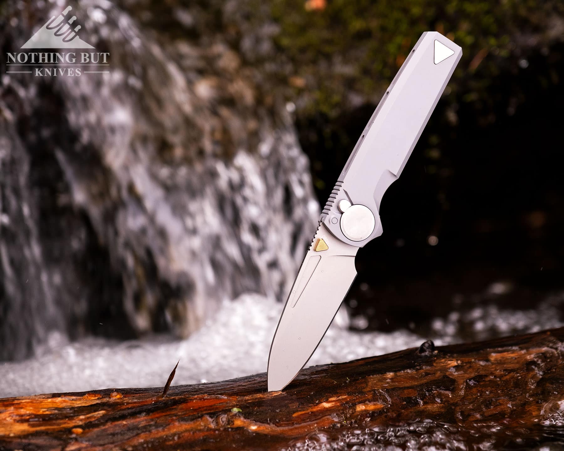 Hogue Mysto Review - Image 11 The Worksharp RMX premium pocket knife shown here with its blade sticking out of a log in a mountain creek.