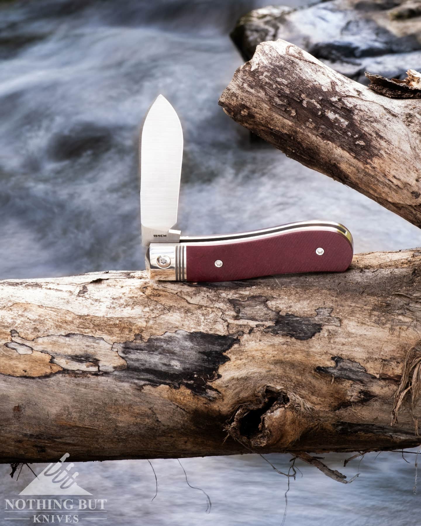 Jack Wolf Knives K9 Jack Review - Image 8 A Jack Wolf slip joint knife with its blade in the half open position balanced on a log over a creek.